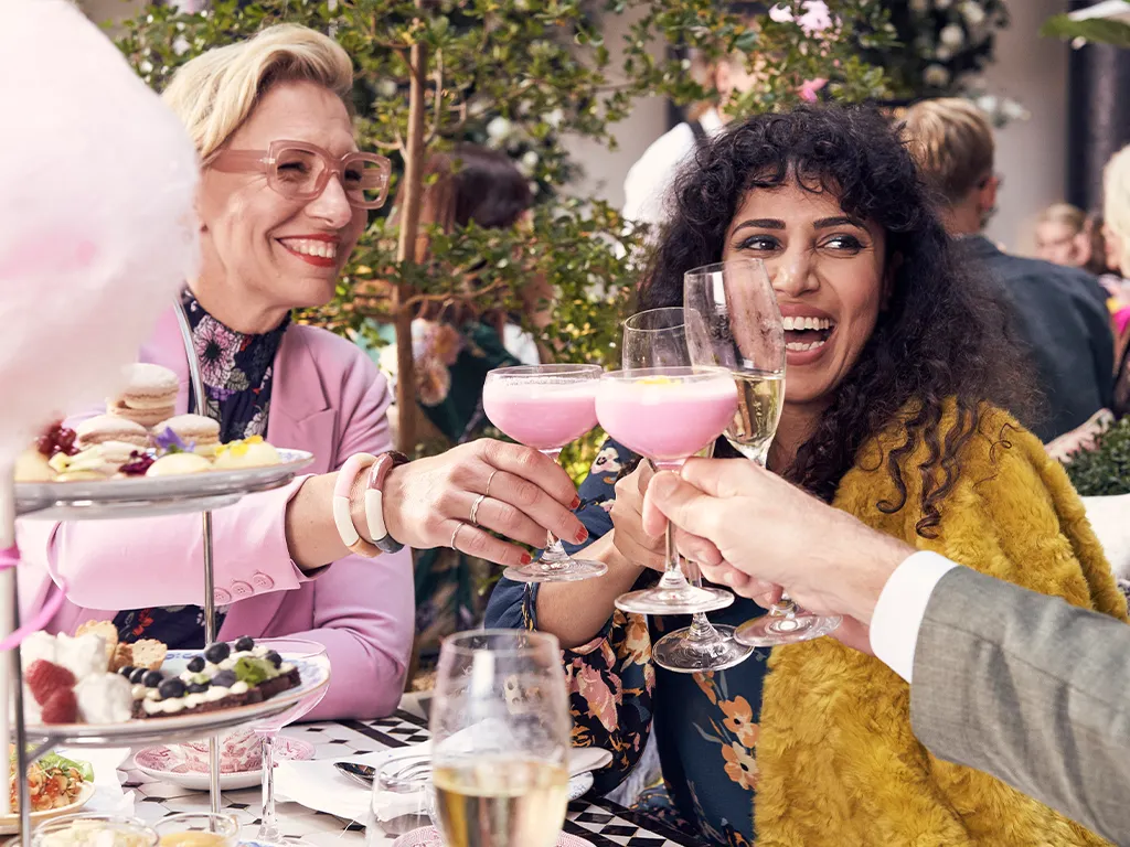 Sällskap som skålar med cocktails och bubbel vid bord med desserter på MJ’S i Malmö